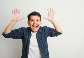 an Excited handsome young Asian man looking up with a happy expression while raising arms isolated on white background photo