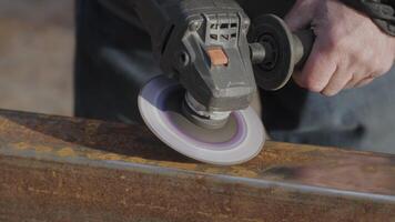 A person is using a handheld polishing tool to smooth a metal surface in an outdoor workshop. The task requires precision and skill. close-up video