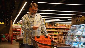 A man 50s 60s looks shocked at a paper check in a grocery supermarket price increase and inflation video