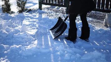 Dedicated homeowner shovels snow-covered pathway in slow motion, showcasing winter snow removal with physical effort Creating clean track through white landscape systematic winter snow removal. video