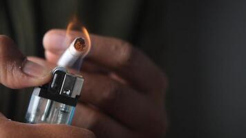An individual lighting a cigarette using a lighter for smoking purposes video