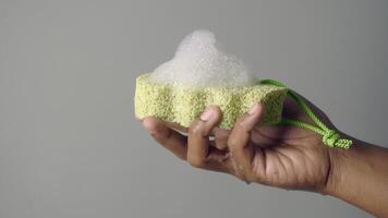 Hand holding a green sponge with soap foam video
