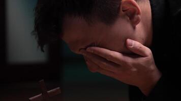 Young man praying and crying in front of cross suffering from depression video