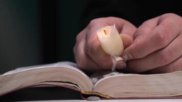 Hands holding extinguished candle dripping wax on open book video