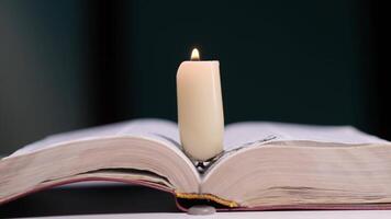 Burning candle resting on open book in dark room video