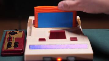 Person inserting cartridge into retro game console with controller video