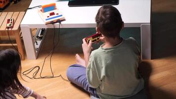 Two kids playing with a retro game console at home video