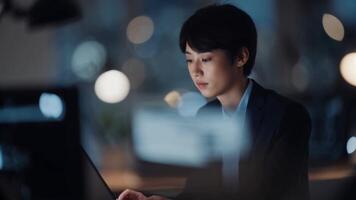 A woman in a business suit is working on her laptop video