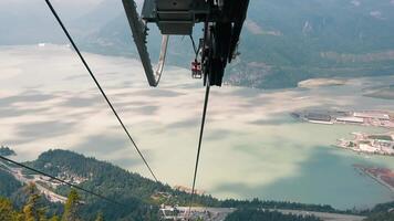 Squamish-Lillooet Canada 20.09.2024 Cable cars descending over waterfront with mountains in background. This image captures cable cars descending towards a scenic waterfront, with a backdrop of video