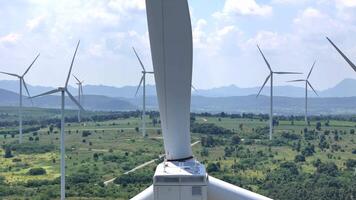Close up view of a wind turbine nacelle with large blades, surrounded by multiple turbines in a green landscape, emphasizing renewable energy technology, sustainability, and innovation. video