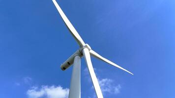 picturesque wind farm under a clear blue sky, showcasing rows of towering wind turbines spread across a lush green landscape, symbolizing renewable energy and sustainable development. video
