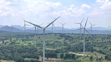 wind farm under a clear blue sky, showcasing rows of towering wind turbines spread across a lush green landscape, symbolizing renewable energy and sustainable development. video
