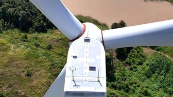 Close up view of a wind turbine nacelle with large blades surrounded by multiple turbines in a green landscape, emphasizing renewable energy technology, sustainability, and innovation. video