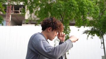Man performing an o utdoor stretching routine in a park. Wearing casual fitness attire, he extends his body gracefully, surrounded by lush greenery and a peaceful urban setting. video