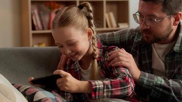 Unhappy Caucasian parent dad father touch little girl play mobile phone game girl child ignoring sad man male at home kid daughter type screen gadget addicted schoolgirl app dependence family trouble video