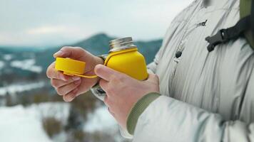 Portrait of young man wearing winter coats, drinking hot coffee or tea looking at amazing mountain top view outdoors video