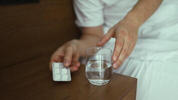 Unwell caucasian man got a sickness, close up man taking a pills and drinking water in a drinking glass after wake up in morning. video