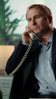 Vertical Intelligence officer on a secure line answering phone call in CIA safe house, gathering field information from undercover informants scattered around the city. Sensitive details. Camera B. video