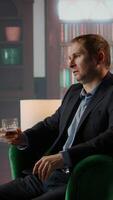 Vertical Gallant investor consultant engage in a meaningful conversation with a friend, enjoying a fine scotch and making propositions for a new business opportunity at the elite social club. Camera A. video
