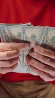 Man counting US Dollar bills, close-up. Vertical video