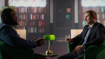 Gallant investor consultant engage in a meaningful conversation with a friend, enjoying a fine scotch and making propositions for a new business opportunity at the elite social club. Camera A. video