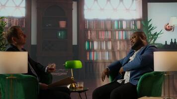 Diverse intelligence duo review a confidential hard disk over a drink, headquarters meeting for data security and team collaboration. Secret agents protecting crucial CIA information. Camera A. video