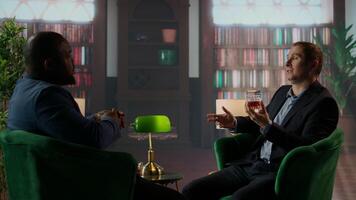 Elegant old money gentlemen in a refined upper class library meeting to discuss business, agreeing on a partnership with a dapper style in an luxury social club environment. Estate heirs. Camera A. video