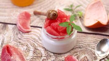 homemade sweet yogurt in a glass jar with pieces of red ripe grapefruit and honey, on a wooden table video