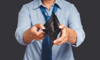 A man in blue shirt hands opens an empty wallet while standing on a gray background photo