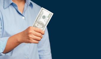 Close-up of hand holding US dollars banknotes while standing on a blue background photo