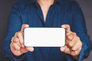 Close-up of hands holding a white blank screen smartphone while standing on a gray background photo