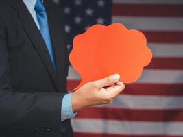 Hand businessman holding a blank red speech bubble while standing on the American flag background photo