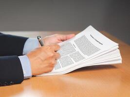 Hand of a businessman in a suit signing on lease contract or agreement while sitting in the office photo