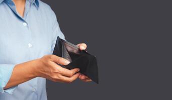 Close-up of hands man opening an empty wallet while standing on a gray background photo