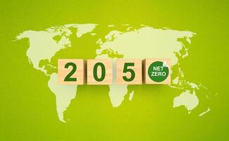 Wooden cubes with text 2050 and net-zero icons over the world map on a green background photo