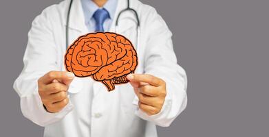 Doctor in uniform holding a white head with a red brain symbol while standing on a gray background photo
