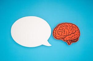 White speech bubble and a brain shape made from paper on a blue background photo