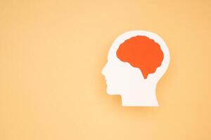A brain shape made from paper on a light orange background photo