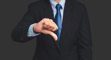 Negative concept. Close-up of a businessman's hand showing thumbs down while standing on a gray background photo