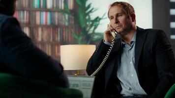 Intelligence officer on a secure line answering phone call in CIA safe house, gathering field information from undercover informants scattered around the city. Sensitive details. Camera B. video