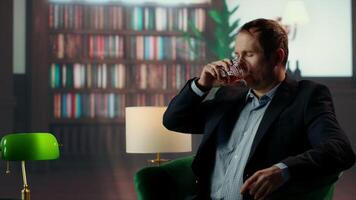 Old money elite gentleman drinking strong whiskey due to stress in a luxurious classy lounge, being dizzy with a headache. High society member getting tipsy, day drinking. Camera B. video