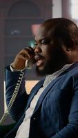 Vertical Black professional spy uses a secure landline phone to discuss case details with his informants, gathering confidential information to solve safety mission. Untraceable phone call. Camera A. video