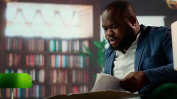 Two men intelligence officers analyzing sensitive information over whiskey, portraying dedication and the professionalism of solving a secret mission. Top secret data at the bureau library. Camera A. video