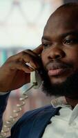 Vertical Black professional spy uses a secure landline phone to discuss case details with his informants, gathering confidential information to solve safety mission. Untraceable phone call. Camera B. video