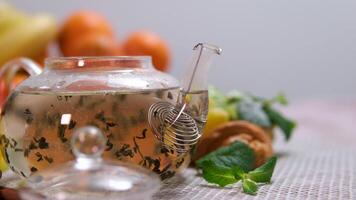 Close up of green tea in teapot and cup on white wooden table. video