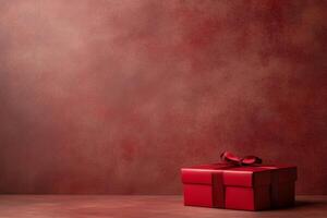 A red gift box with a bow on a textured red background, suggesting celebration or gifting. photo