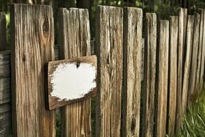 A rustic wooden fence with a blank sign attached, set in a natural environment. photo