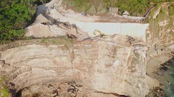 Escalators digging and engineering the rock on cliff coastline near Uluwatu. Drone view video