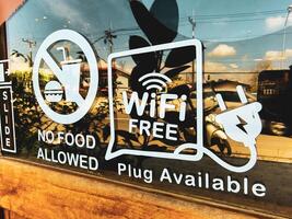 Cafe Window Signage Displaying Free WiFi and No Food Policy with Reflections of Outdoor Scenery photo