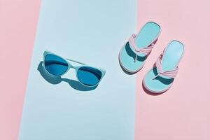 A pair of blue and pink flip flops and sunglasses on a pink and blue background photo